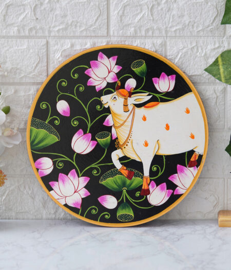 Pichwai Painting: This beautiful pichwai painting features a serene white cow adorned with a vibrant floral headdress